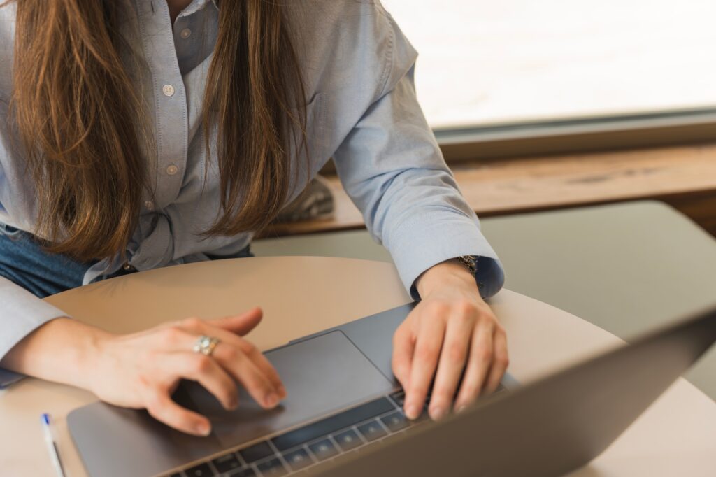 Business woman in light blue shirt typing on her laptop